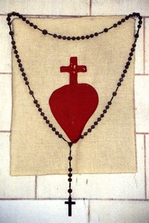 Sacré-Cœur et chapelet accrochés au mur derrière l'autel. Sacré-Cœur et chapelet accrochés au mur derrière l'autel.